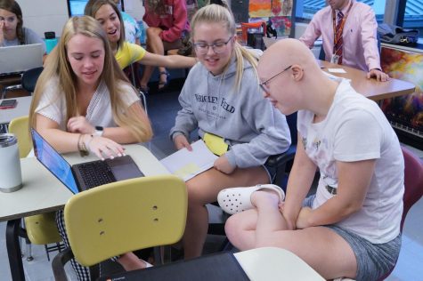 Nathalie young sits with Gracie Phillips and Maddie Kaasa around a laptop.