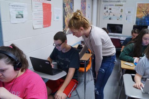 Robbie Wittig watches his latop as Ally Sparks stands over him. 