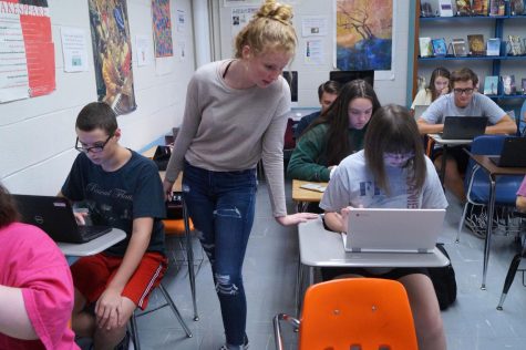 Ally Sparks stands between Robbie Wittig and Katie Godfrey. She's watching Godfrey's laptop screen.