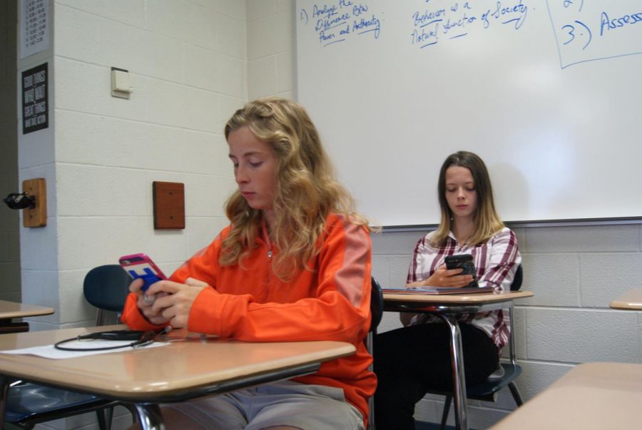 Kimmy Cane (12) and Athena Patton (10) sit in house on their phones.