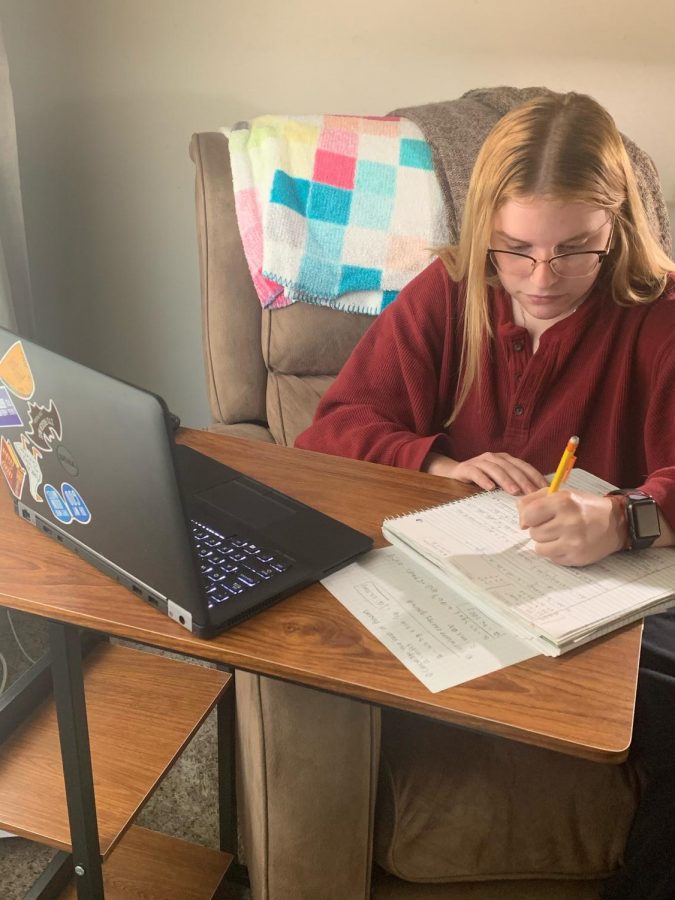 Junior Deanna Blasko sitting in her living room working on her online academy homework.