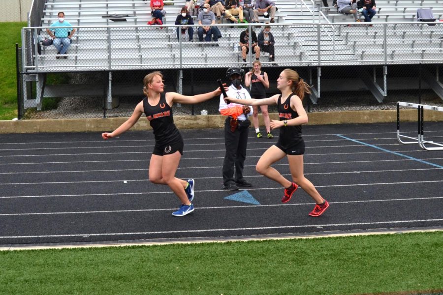 Sophomore Rowan Hering hands off the baton to freshman Ella Fronduti in the 4x800 relay.