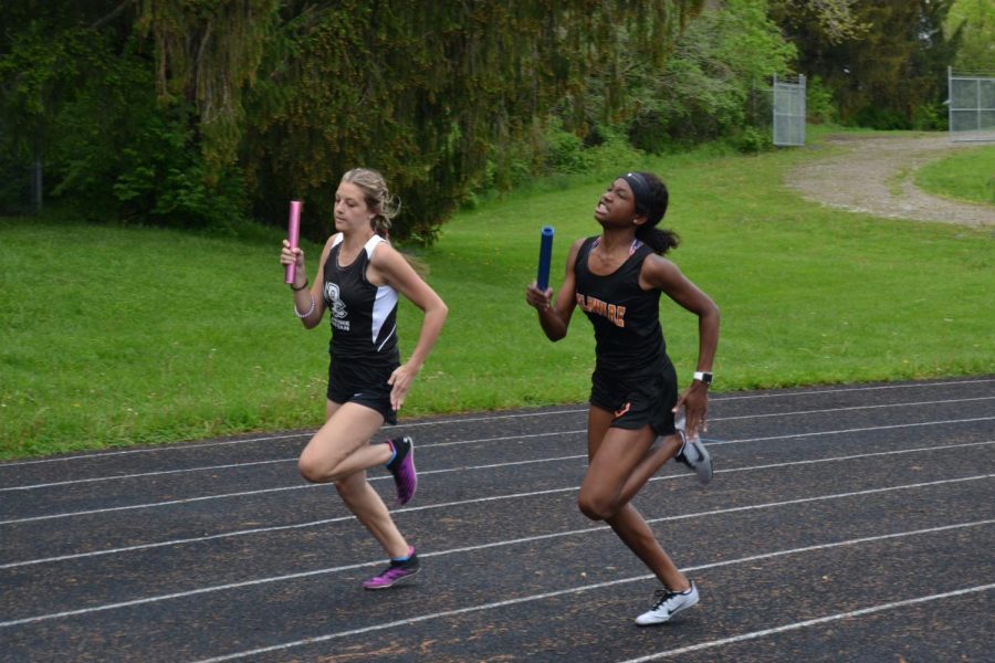 Student athletes from two different teams running relay next to each other