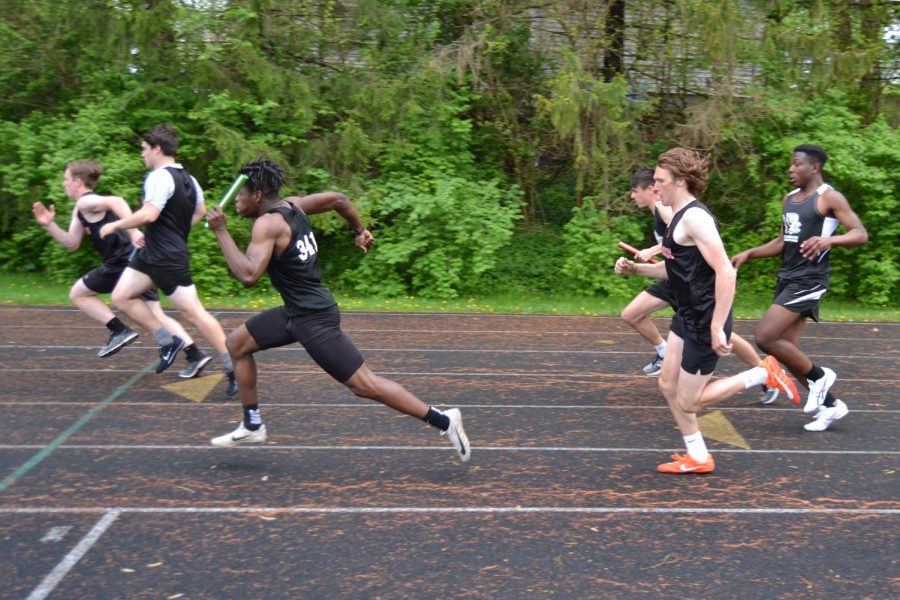 Two student athletes running after baton handoff