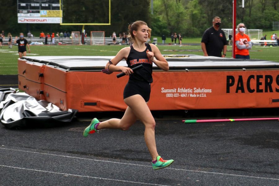 Student athlete running with relay baton mid stride