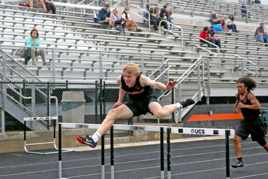 Two athletes clear hurdles