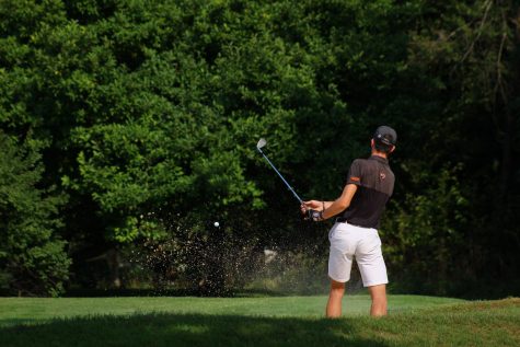 golfer chips out of the bunker.