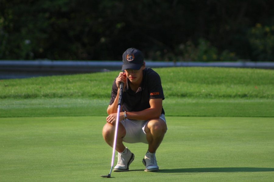 golfer squats down to read his putt.