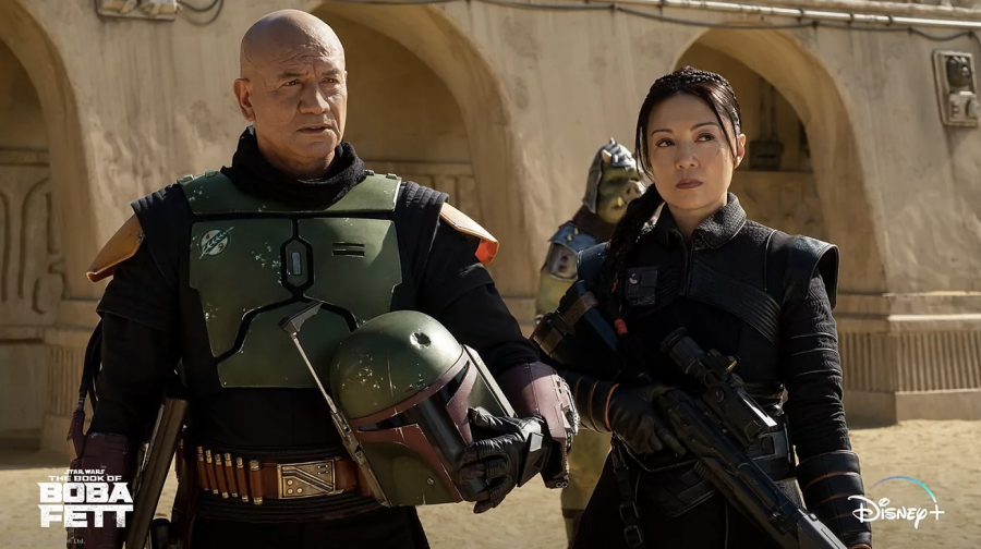 Boba Fett (Temuera Morrison) and Fennec Shand (Ming Na-Wen) observe the streets of Mos Espa in The Book of Boba Fett. The series is now streaming in its entirety on Disney+.