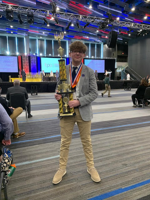 Junior Sam Hall standing with his trophy after getting second-place at the BPA state competition.