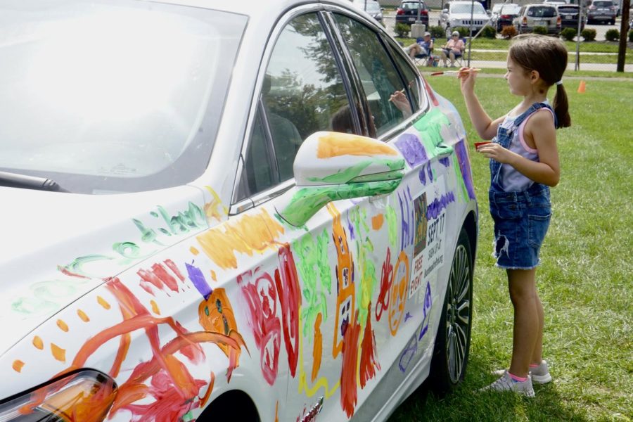 A little girl helps contribute to the community art car. This weekend’s theme was Halloween.