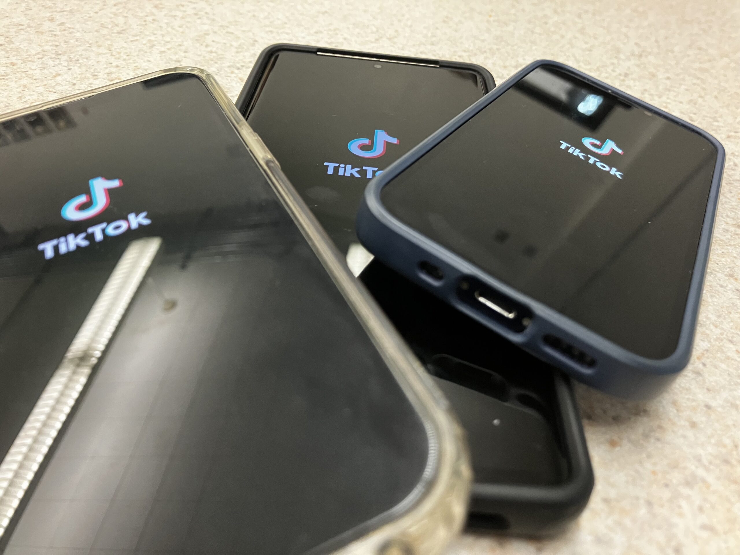 Multiple phones sit on a table with the Tiktok app pulled up. Tiktok has been a hot debate topic in politics recently