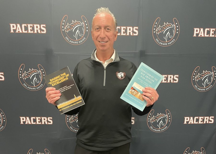 Hayes Principal Ric Stranges stands holding two of his newly released books.
