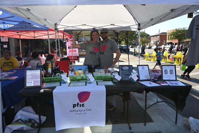 Members of the Anderson family stand around a booth at Delawares First Friday event, intending to raise awareness for the rare liver disease PFIC.