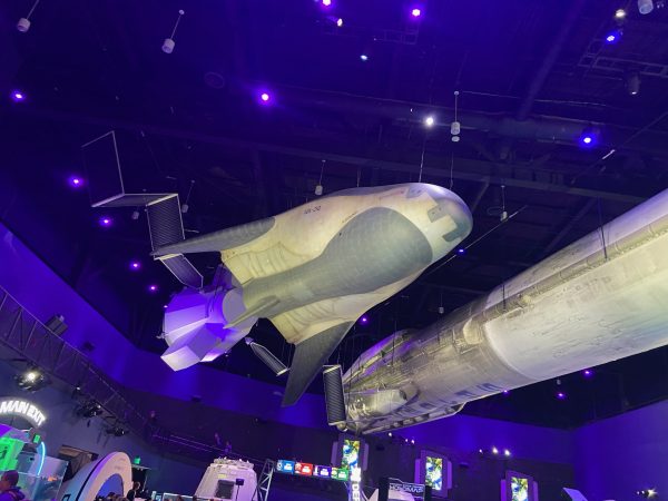 A mockup of Dream Chaser hangs next to a used Falcon 9 booster at the Kennedy Space Center. Both crafts have been used or designed as part of NASA's Commercial Crew Program.