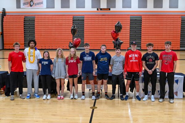 Students athletes group together for a picture following their college signings.