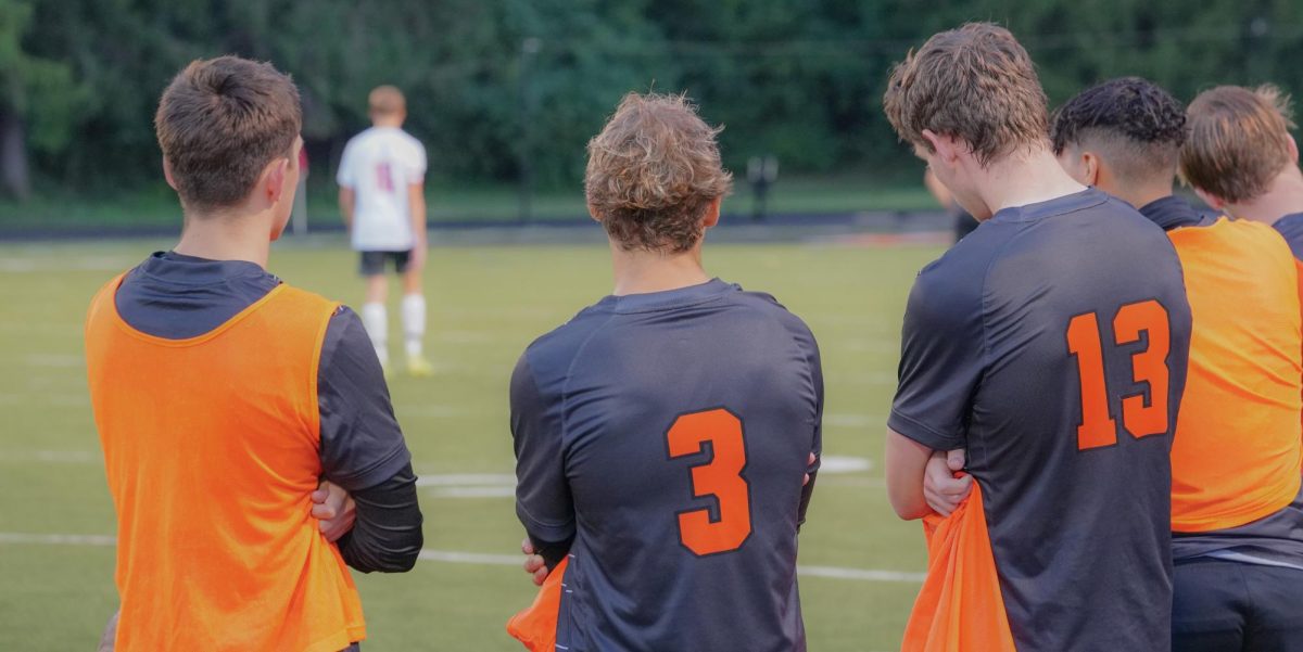 Seniors Ty Huff and Isaac Isenbarger and Junior Owen Marsch watch from the sideline.