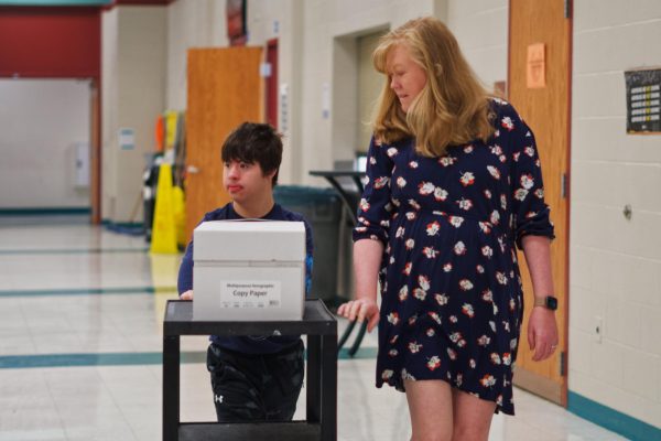 Freshman Matt Wolfe and Intervention Specialist Rebecca Saunders roll the paper cart to their next stop.